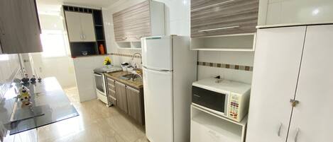 Una cocina moderna con alacenas blancas, microondas integrado y horno de acero inoxidable.