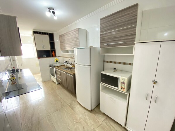 A modern kitchen with white cabinets, a built-in microwave, and a stainless steel oven.