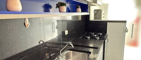 A modern kitchen with a black countertop, stainless steel sink, and a microwave.