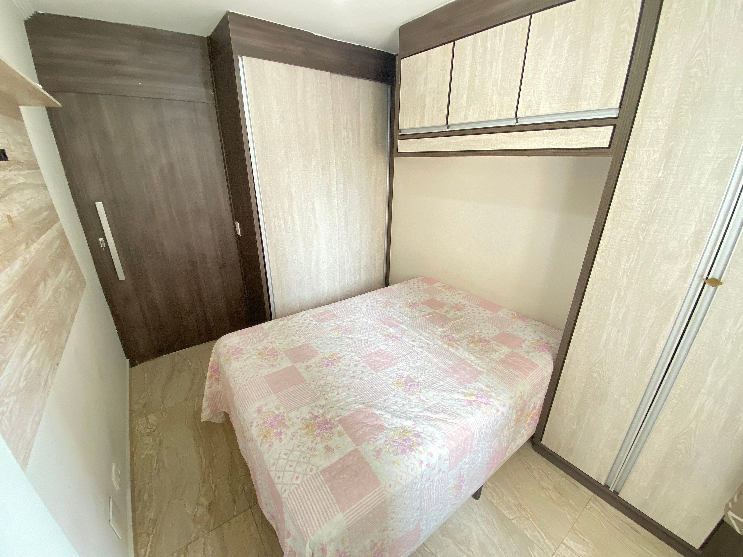 A bedroom with a bed, a wardrobe, and a built-in cabinet.