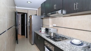 A modern kitchen with dark cabinets, a stainless steel refrigerator, a microwave, a gas stove, and a sink. - Modern and chic apartment | Rabat city center (Rabat)