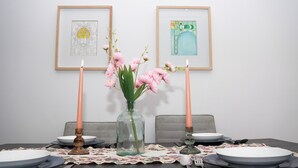A dining table set with plates, cutlery, and candles, with artwork on the wall behind. - Modern and chic apartment | Rabat city center (Rabat)