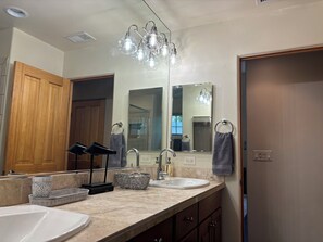 A bathroom with two sinks, a mirror, and a ceiling light fixture.