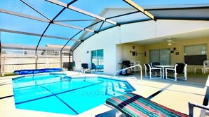 A pool area with a glass enclosure, lounge chairs, and a table. - Ref 317. Stunning villa with own pool near Disney (Four Corners)