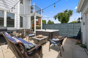 A patio with wicker furniture, a fire pit, and a hot tub. - Group Retreat with Hot Tub, Gym, Sauna, and Fire Pit (Englewood)