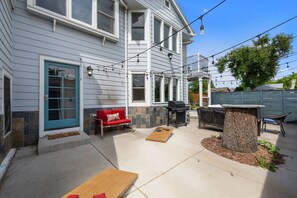 A house with a patio, a red sofa, a barbecue grill, and a wooden table. - Group Retreat with Hot Tub, Gym, Sauna, and Fire Pit (Englewood)