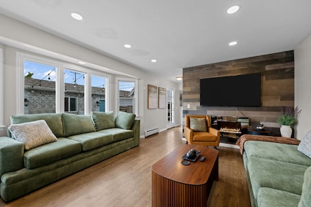 A modern living room with a green sofa, a wooden coffee table, and a fireplace.. Group Retreat with Hot Tub, Gym, Sauna, and Fire Pit