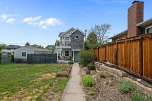 A residential property with a paved pathway, a wooden fence, and a brick chimney. - Group Retreat with Hot Tub, Gym, Sauna, and Fire Pit (Englewood)