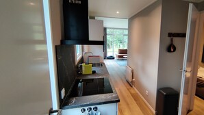 Una cocina moderna con un horno negro, una tabla de cortar amarilla y una ventana con vistas a un jardín.