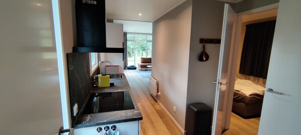 Una cocina moderna con un horno negro, una tabla de cortar amarilla y una ventana con vistas a un jardín.