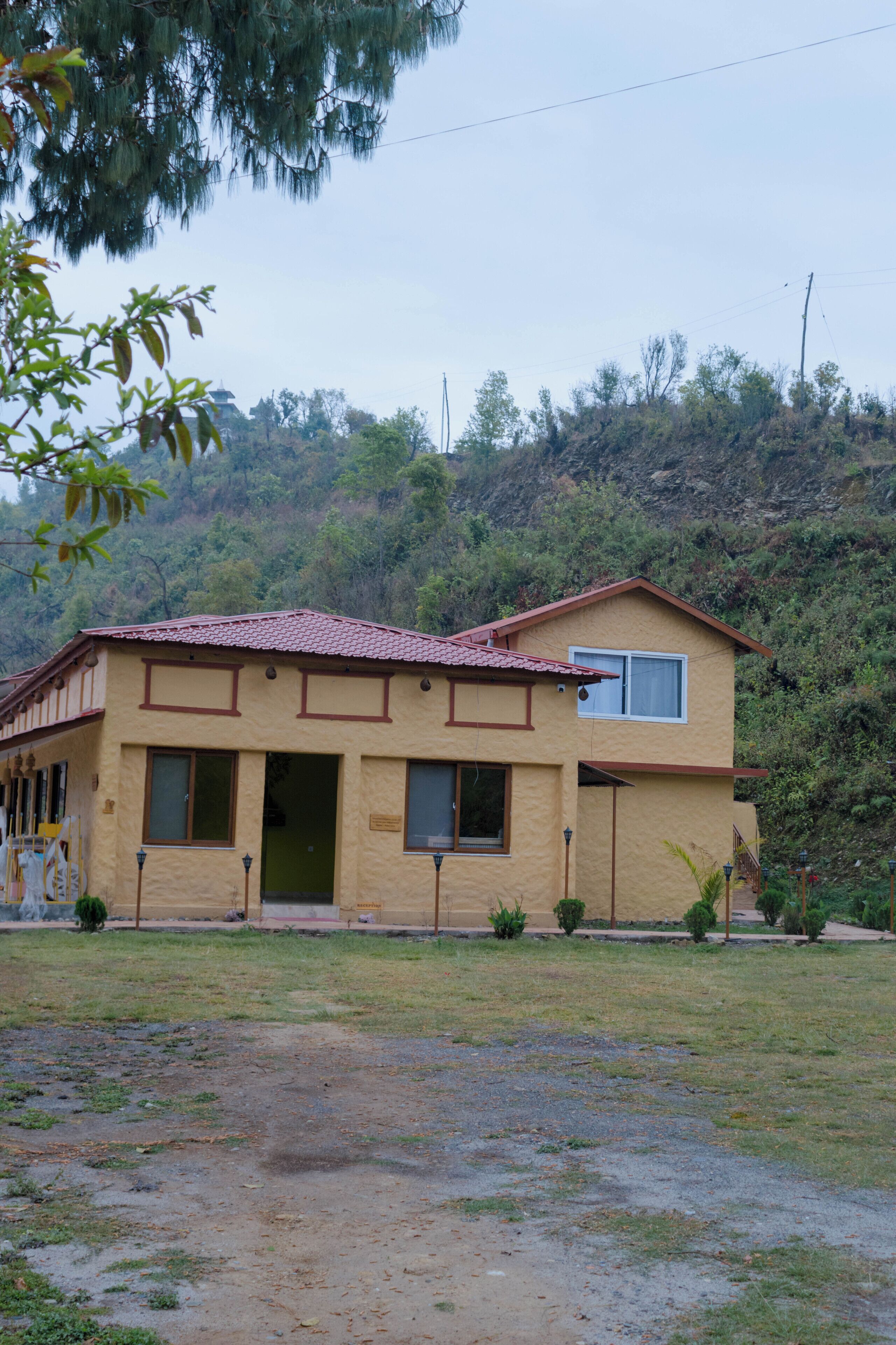 A two-story house with a red-tiled roof, a front porch, and a small front yard.