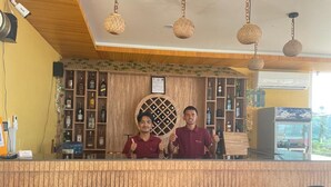 A reception area with a wooden counter, two black chairs, and a wall of liquor bottles. - Mattikhan Mountain View Resort (Pokhara)