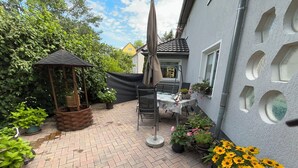 A patio with a gazebo, a table with chairs, and potted plants.