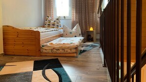 A bedroom with a wooden bed, a small bedside table with a lamp, and a window with curtains.