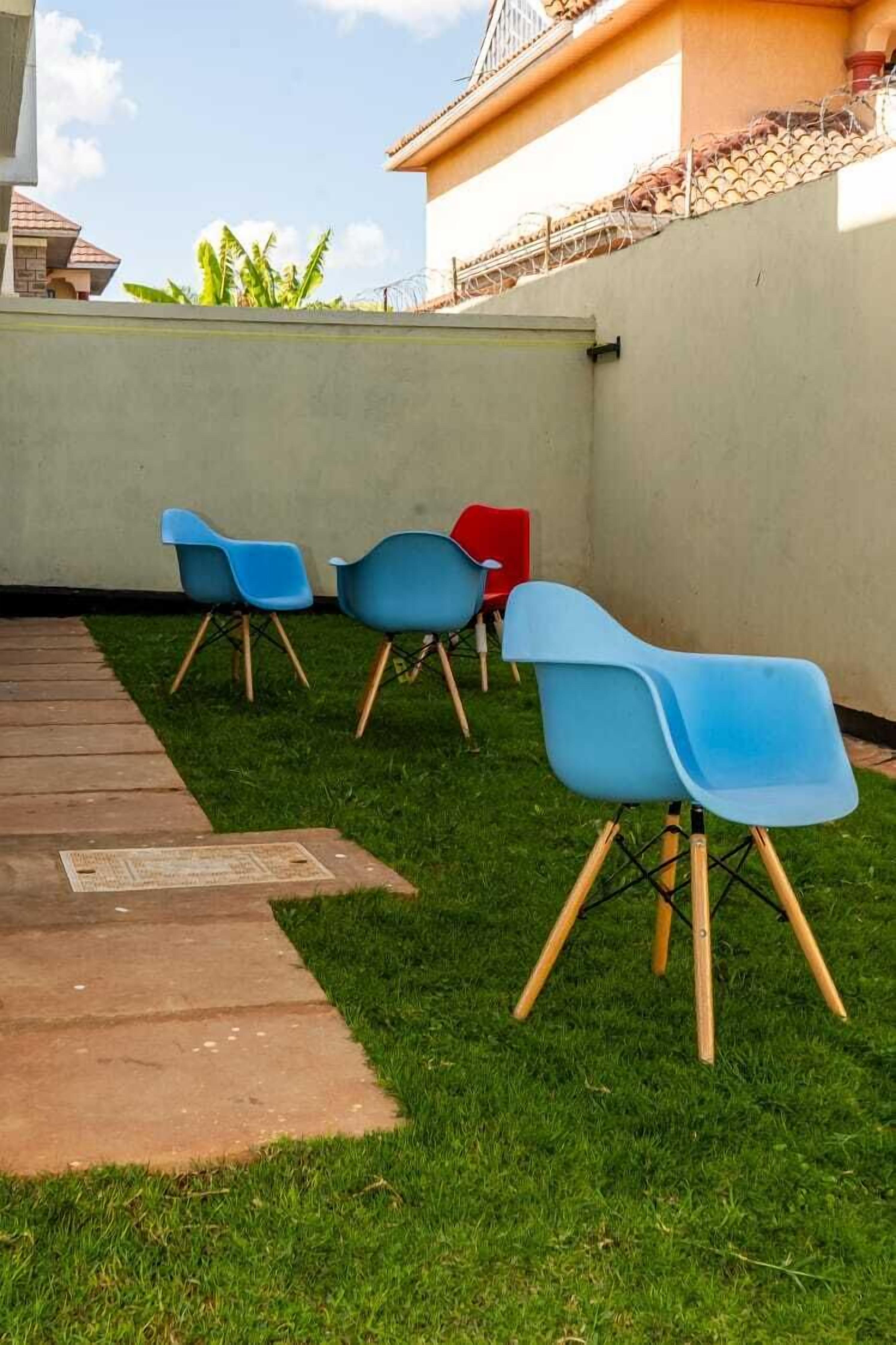 A patio area with three chairs, a concrete path, and a grassy lawn.