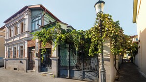 A two-story building with a traditional architectural style, featuring a prominent entrance with a metal gate and a street lamp nearby.