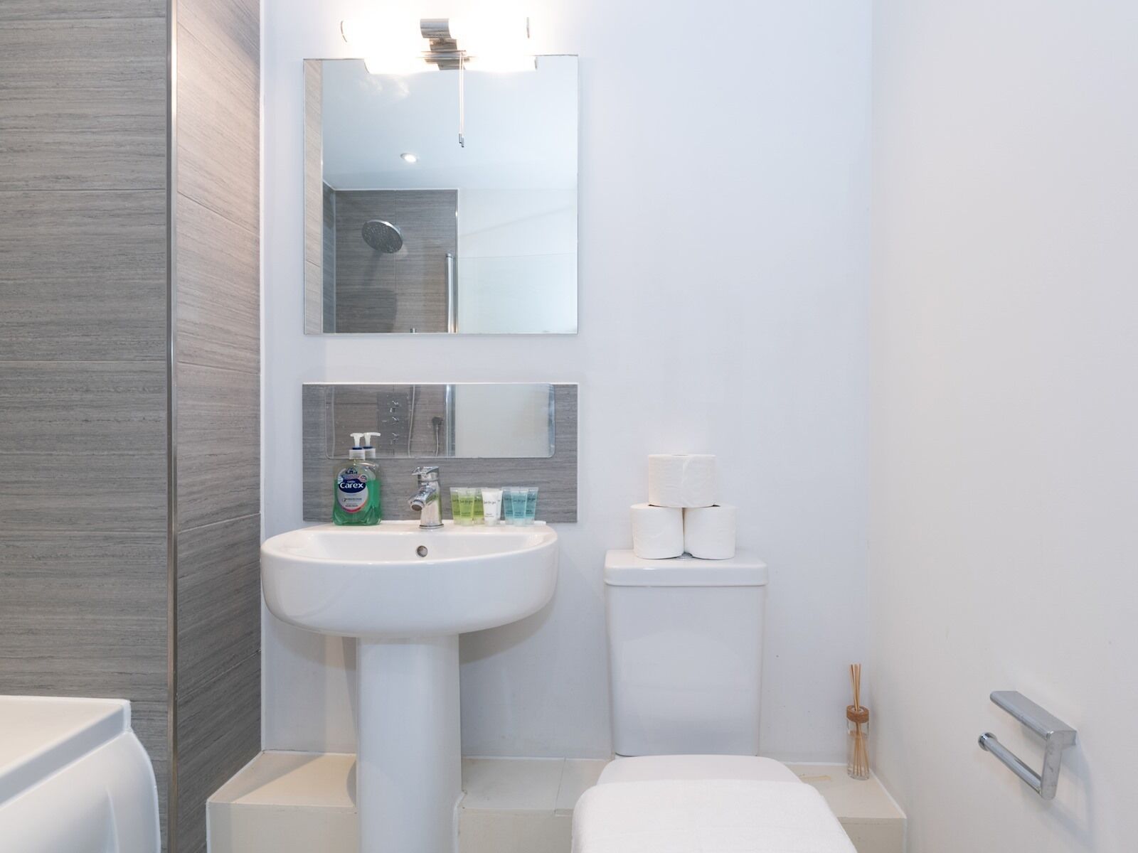 Une salle de bain moderne avec un lavabo blanc, un miroir et des toilettes.