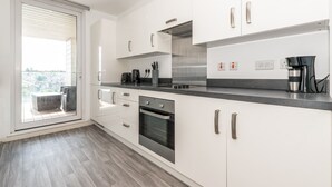 Une cuisine moderne avec des meubles blancs, des appareils en acier inoxydable et un plan de travail noir.