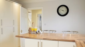 Una cocina moderna con armarios blancos, encimera de madera y un reloj en la pared.