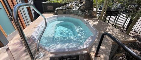 Un bain à remous avec un panneau indiquant les heures d’ouverture du spa, de 10h à 22h.