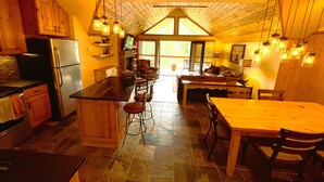 Una cocina con una isla central, armarios de madera, un refrigerador y lámparas colgantes.