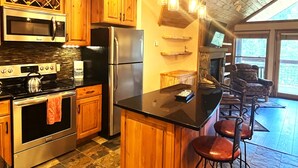 Una cocina moderna con electrodomésticos de acero inoxidable, armarios de madera y una zona de bar con taburetes.