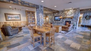 Un salón espacioso con chimenea de piedra, una mesa de comedor de madera y asientos cómodos.