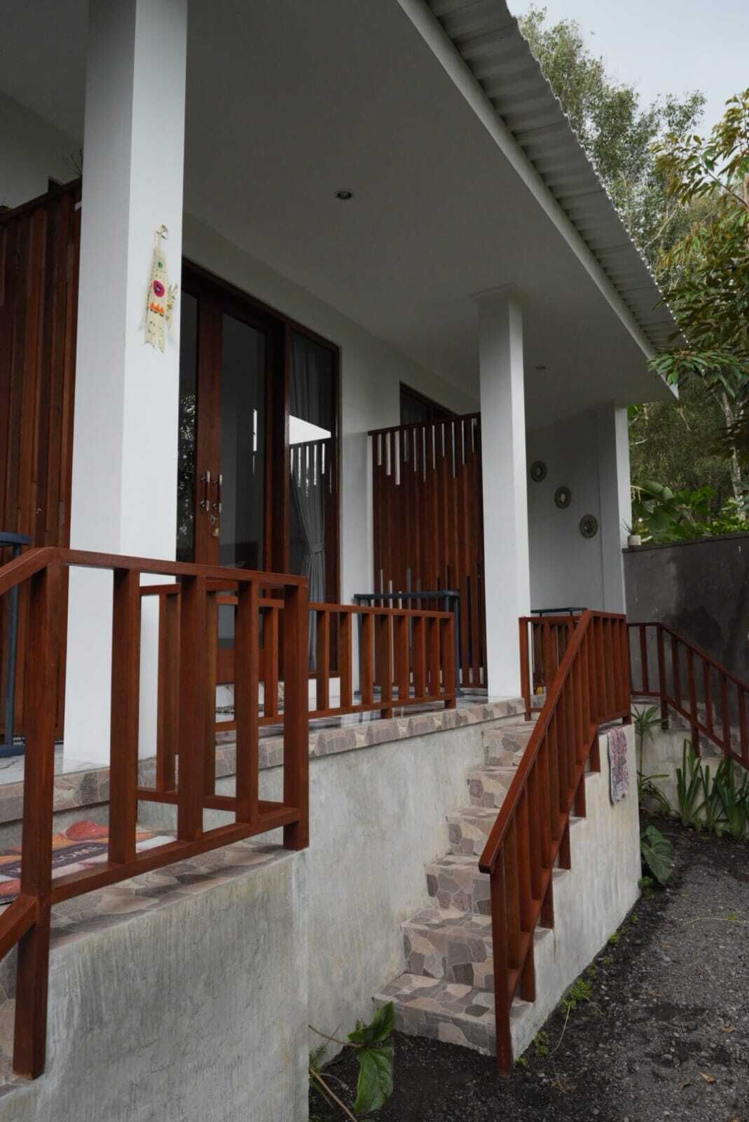 Een huis met twee verdiepingen, een veranda, stenen trappen en houten leuningen.
