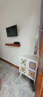 Una habitación con televisión montada, repisa de madera y mueble de cerámica con diseños coloridos.