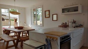 A modern kitchen with a wooden table, a white countertop, and a built-in oven. - Charming house with swimming pool near the Golf d'Arcachon (La Teste-de-Buch)