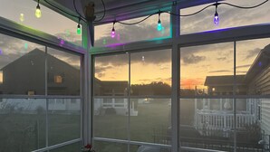 Une pièce dotée de grandes fenêtres, d’un patio et offrant une vue sur une maison et le ciel.
