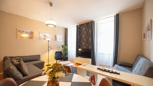Ein modernes Wohnzimmer mit einer Couch, einem Esstisch und einem Fernseher.