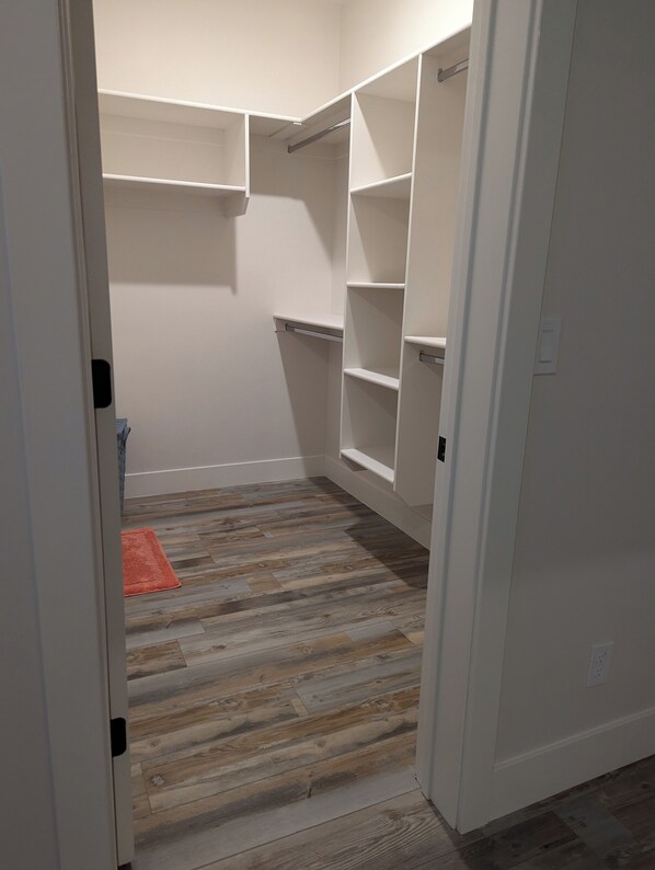 A walk-in closet with wooden flooring and white walls.