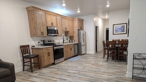A modern kitchen with wooden cabinets, stainless steel appliances, and a herringbone wood floor. - Charming 2-bedroom apartment with WiFi , AC and Heating in serene Enterprise (Enterprise)