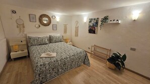 A bedroom with a patterned bedspread, bedside tables, wall-mounted decor, and a wooden bench. - La Maison Bouganville charming guest house in the city center of Salerno (Salerno)
