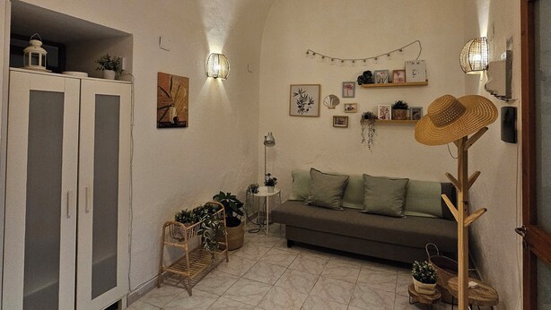 A cozy living room with a sofa, a wooden floor lamp, and a hanging light fixture. - La Maison Bouganville charming guest house in the city center of Salerno (Salerno)
