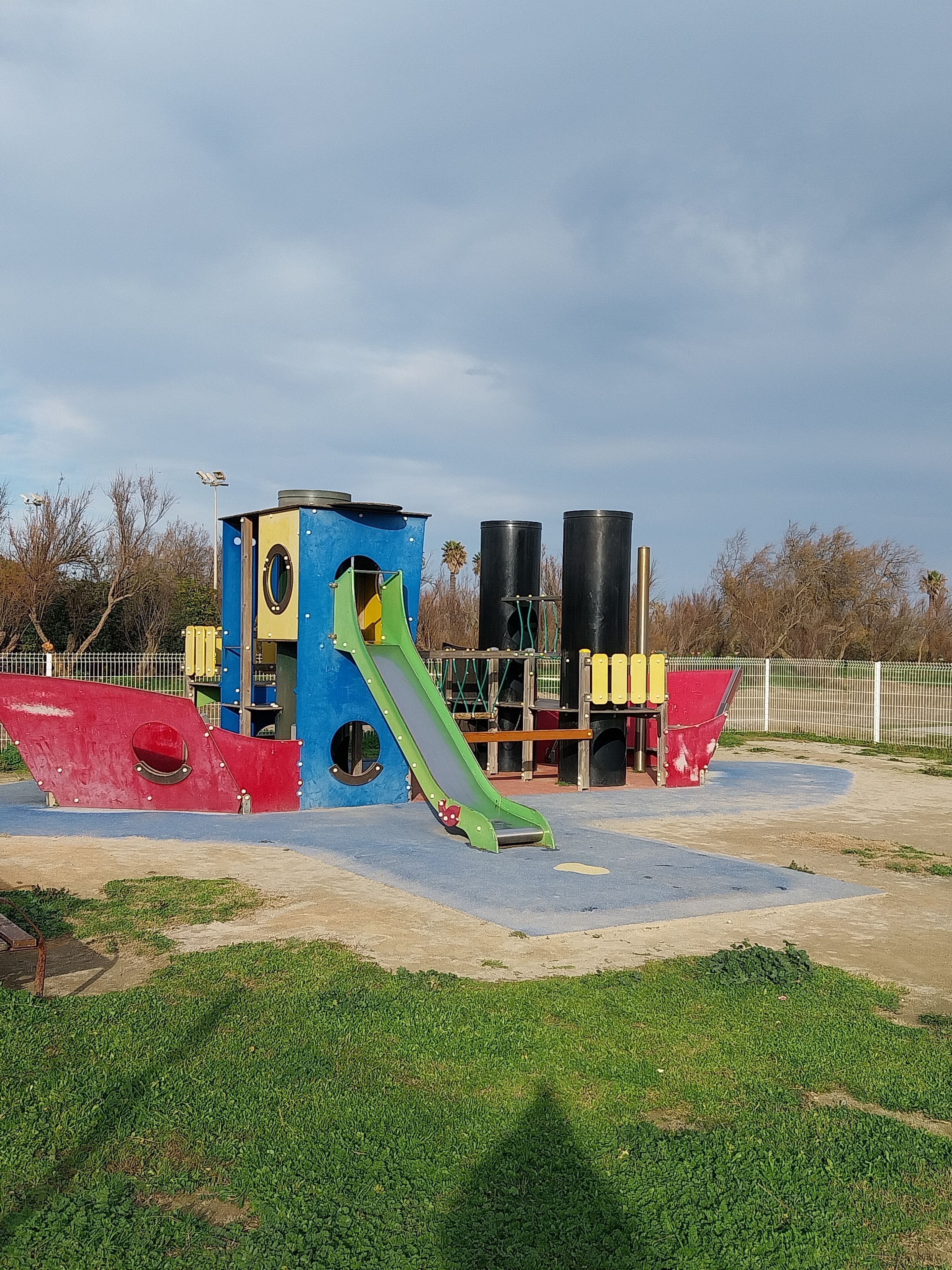 A playground with a slide, climbing structures, and a fenced area.