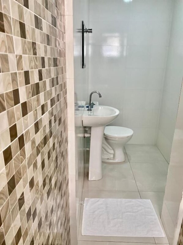 A bathroom with a tiled wall, a sink, and a toilet. - Hotel Praça da Árvore - São Paulo Expo (São Paulo)
