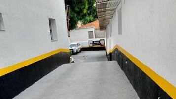 A narrow, concrete pathway with yellow and black stripes, leading to a building entrance.