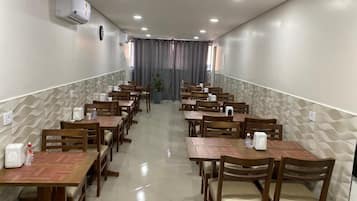 Un espace repas comprenant plusieurs tables et chaises en bois, disposées en rangées.