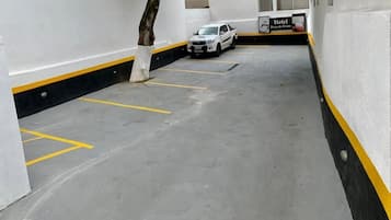 A parking garage with marked parking spaces and a white car parked in one.