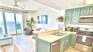 A modern kitchen with green cabinets, a built-in oven, and a large island with a sink.