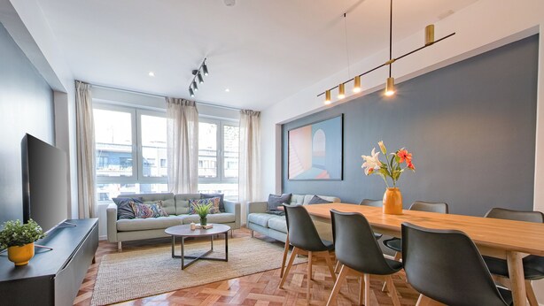 Un salon moderne comprenant un canapé, une table basse et un coin repas avec des chaises et une table en bois.