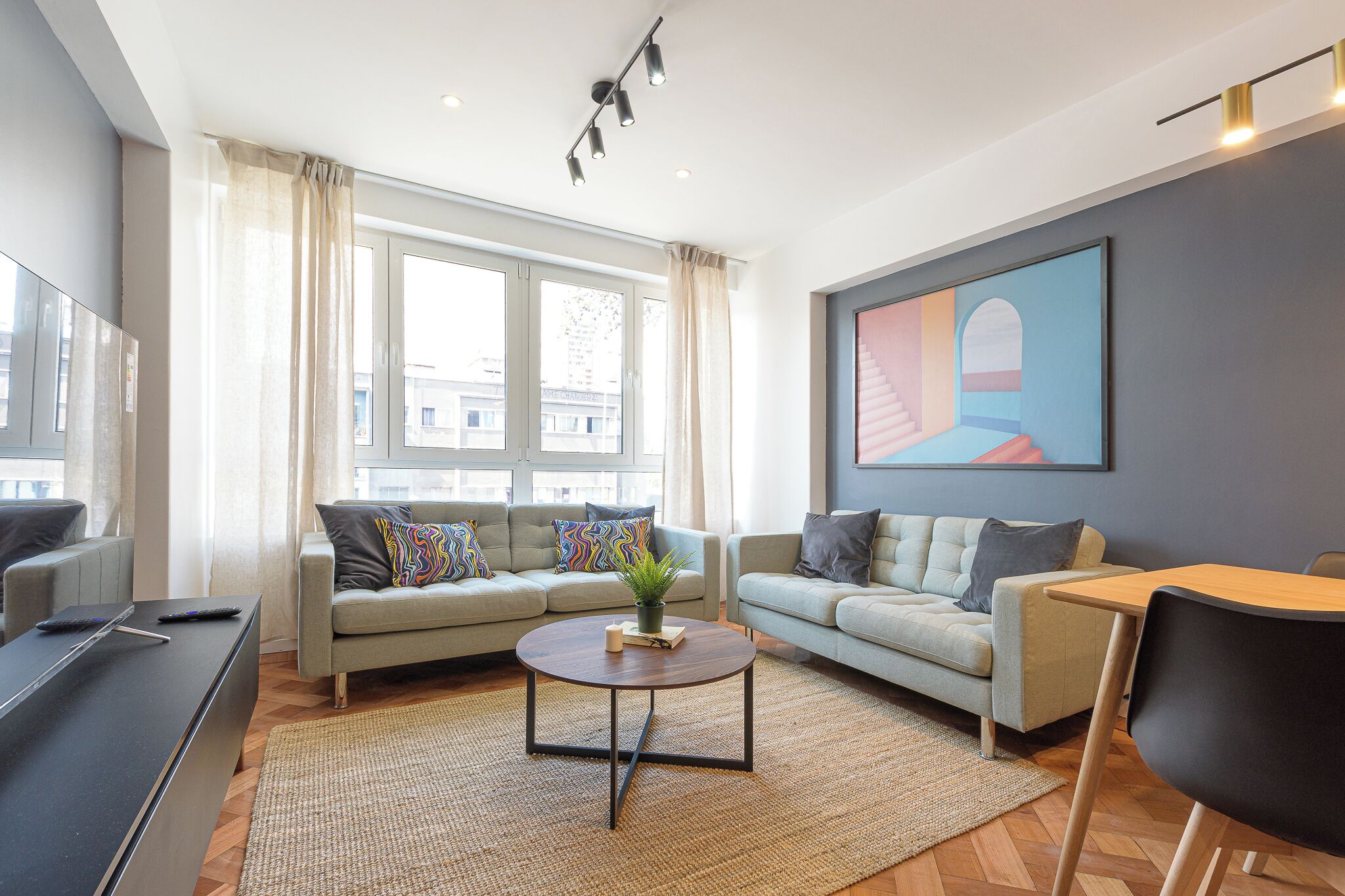 A modern living room with a sofa set, a coffee table, and a painting on the wall.