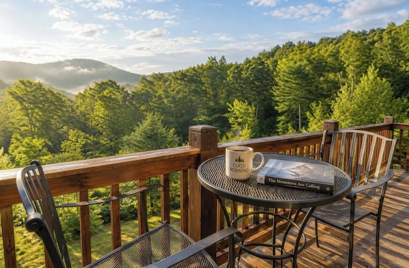 A deck with a table and chairs, a book, and a mug.