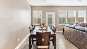 A dining area with a table and chairs, a sofa, and a door leading outside. - Fun Family Friendly Home Great Location in Houston 3BDR 2.5 Bath (Houston)