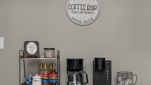 En køkkenbordplade med kaffestation, inklusive kaffemaskine, sukker og kaffebønner.