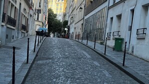 A cobblestone street lined with historic buildings, some with balconies and large windows, under a clear sky. - Charming apartment (Paris)