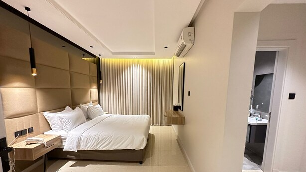 A modern hotel room with a large bed, bedside tables, a mirror, and a view of the bathroom. - XYZ Hotel Qurtoba (Riyadh)