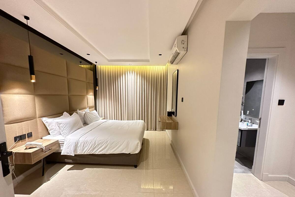 A modern hotel room with a large bed, bedside tables, a mirror, and a view of the bathroom.